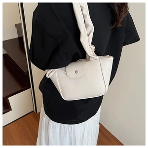 Close-up detail of cream white pleated handle and magnetic flap closure on the shoulder bag