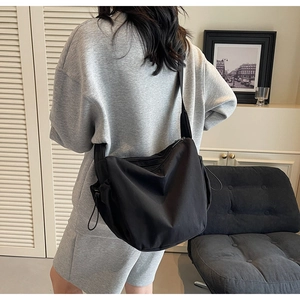 Rear view of a minimalist large capacity black crescent canvas bag worn cross-body