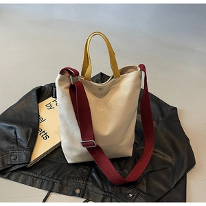 Vue détaillée du sac en toile avec poignée jaune gingembre et bandoulière bordeaux