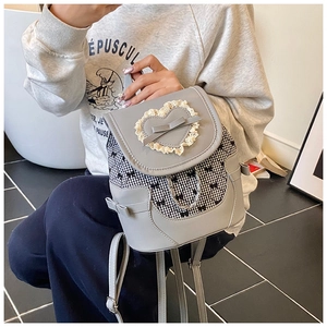 Detail of grey mini backpack with heart lace, checkered pattern and metal chain charm