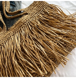 Détail d'un sac cabas en paille bohème avec franges décoratives et texture tressée