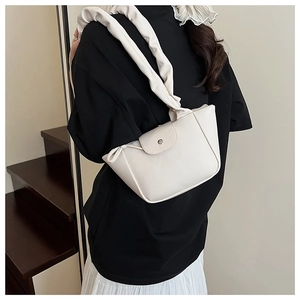 Detail of off-white ruched shoulder strap and matte faux leather texture on the handbag