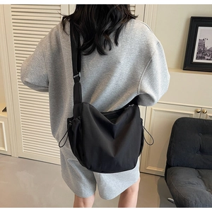 Detailed back view of a black nylon crossbody bag with drawstring details and adjustable strap