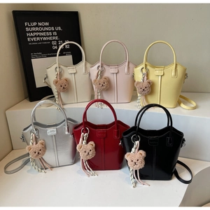 Mini bucket bags in six colors featuring plush bear charms and adjustable leather straps