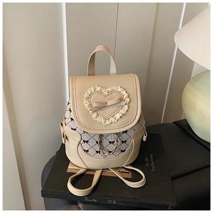 Detail of cream mini backpack featuring lace heart, bow accents, and beige plaid pattern