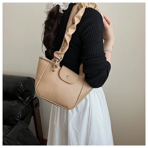 Detail view of stylish pleated strap and matte leather texture on apricot shoulder bag