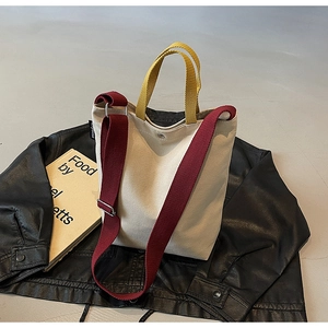 Vue détaillée du sac en toile avec poignées jaunes et bandoulière réglable rouge foncé