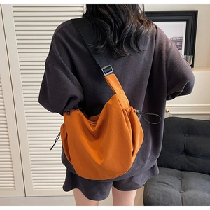 Detail of bright orange crescent canvas bag featuring adjustable black drawstrings