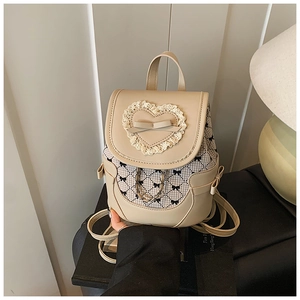 Detail of cream mini backpack featuring lace heart patch and black bow print patterns
