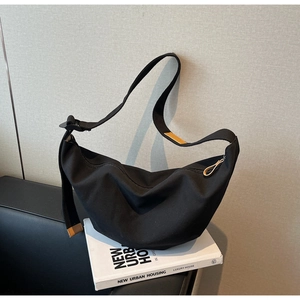 Detail shot of a black minimalist canvas half-moon bag on books for lifestyle display