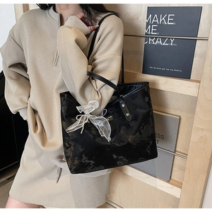 Detail der schwarzen Shopper-Tasche mit weißer Spitzenschleife und geräumigem Design