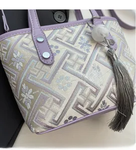 Detailed macro view of purple leather trim, beige floral embroidery, and tassel charm