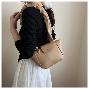 Detail of a smooth PU leather bag with pleated handle and round metallic snap closure