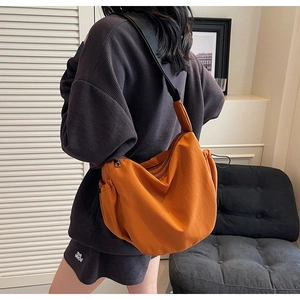 Detail view of large orange canvas hobo bag showing side drawstring and adjustable strap