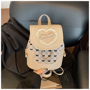 Detailed close-up of beige leather backpack featuring lace heart and metal chain accents