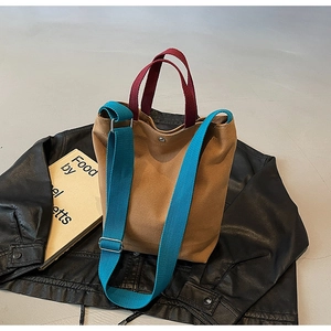 Détail d'un sac cabas en toile avec sangle bleue et fermoir pression sur une veste en cuir