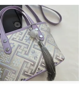 Detail of lavender leather handle and vintage tassel on a jacquard patterned bucket bag