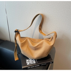 Detail of khaki canvas crescent crossbody bag resting on a book with adjustable strap