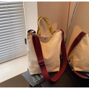 Détail du sac fourre-tout en toile avec bandoulière bordeaux et anse jaune sous la lumière