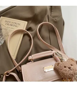 Dettaglio borsa in pelle rosa con bordo a catena, logo oro e ciondolo a orsetto