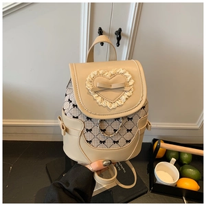 Detail of beige bow-patterned backpack with heart lace and metal chain accent