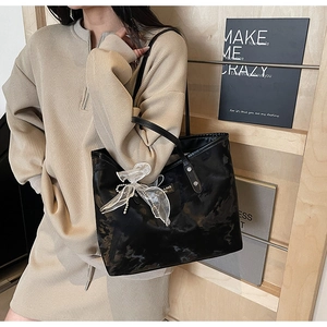 Detail der schwarzen Lack-Tote-Bag mit weißer Netzschleife und Perlenkette am Schultergurt
