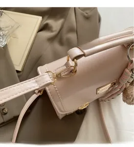 Dettaglio dello zaino in pelle PU rosa con fibbia dorata e cuciture bianche trapuntate