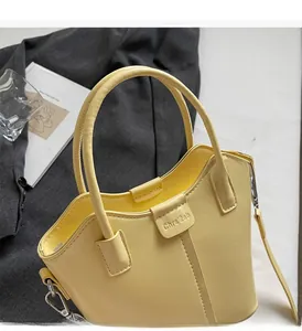 Detail view of bright yellow bucket bag with smooth top handle and metal hook connectors