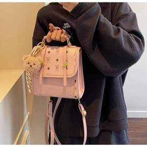 Close-up of pink faux leather backpack with teddy bear pattern and plush charm
