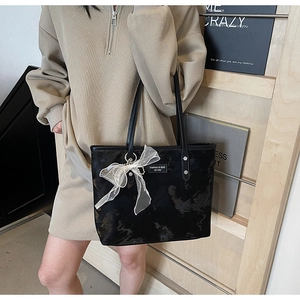 Detail der schwarzen Achseltasche mit Wolkenstruktur und weißer Schleife am Model
