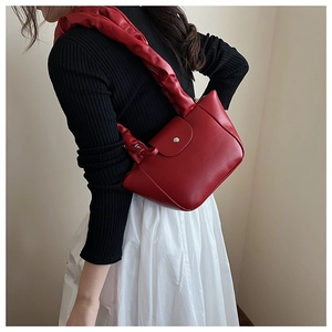 Detail of red pleated shoulder bag showing premium faux leather and silver metal clasp