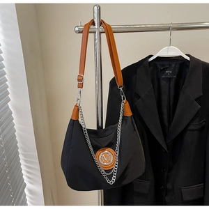 Detail of black nylon shoulder bag with brown leather trim and silver metal chain
