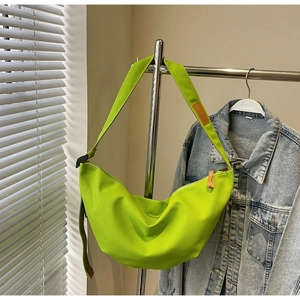Detailed shot of neon green canvas half-moon bag with adjustable wide strap and leather tag