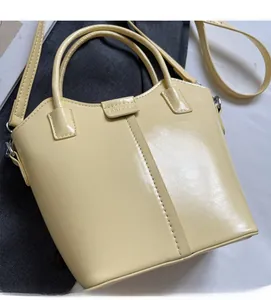 Detail view of a pale yellow PU leather bucket bag with top handles and adjustable strap
