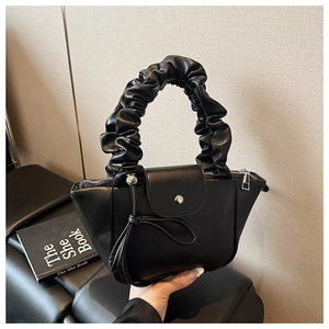 Detail of ruched handle and knot decorative side on black leather shoulder bag