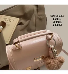 Dettaglio dello zaino in pelle rosa con ciondolo a orsetto e finiture metalliche del manico
