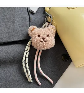 Detail of cute coffee brown plush bear charm with woven ropes on a leather handbag