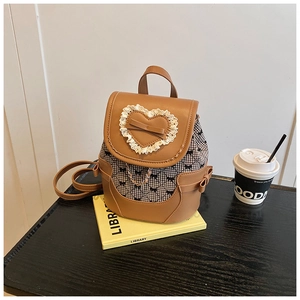 Close-up of brown leather backpack with plaid fabric, lace heart and bow detail