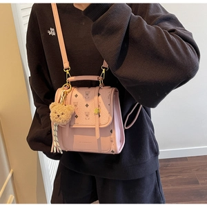 Detailed view of pink crossbody backpack with bear print pattern and plush bear charm