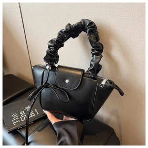 Detail view of the black pleated handle handbag with matte leather and buckle closure