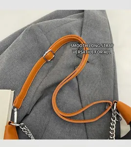 Detail of adjustable orange leather shoulder strap with silver buckle and metal chain links