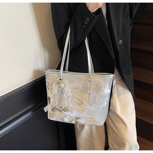 Detail der silbernen Metallic-Tasche mit schickem Schleifenanhänger auf schwarzem Blazer