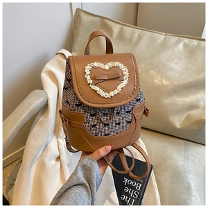 Detail of a brown leather and plaid mini backpack with lace heart and bow details