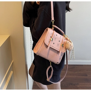 Close-up of pink mini backpack with bear print and plush charm on adjustable strap