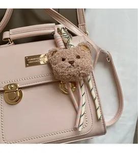 Dettaglio borsa in pelle PU rosa con chiusura in metallo dorato e charm orsetto marrone
