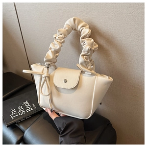 Detail of beige pleated handle handbag with metal buckle closure and textured finish