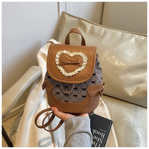 Detail of vintage brown backpack with lace heart patch and black bow patterns