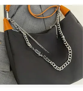 Detail shot of black nylon bag with leather trim and double metallic chain decoration