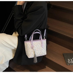 Detail of purple jacquard mini bucket bag with gray tassel held by a person on stairs