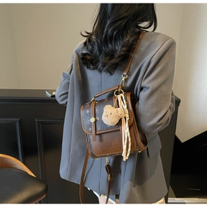Detail of vintage brown monogram backpack with teddy bear charm and pink silk scarf